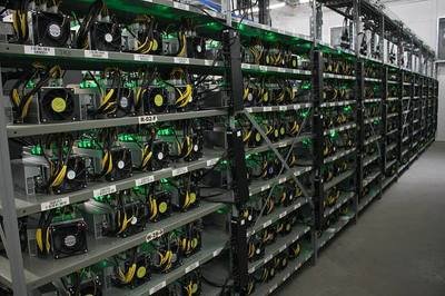 A sprawling cryptocurrency mining farm illuminated by rows of flashing mining rigs